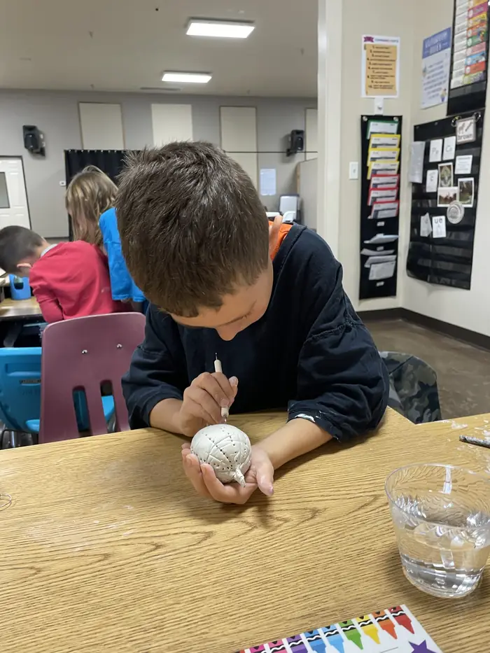 A Cornerstone student carving a pattern into a clay piece in art class
