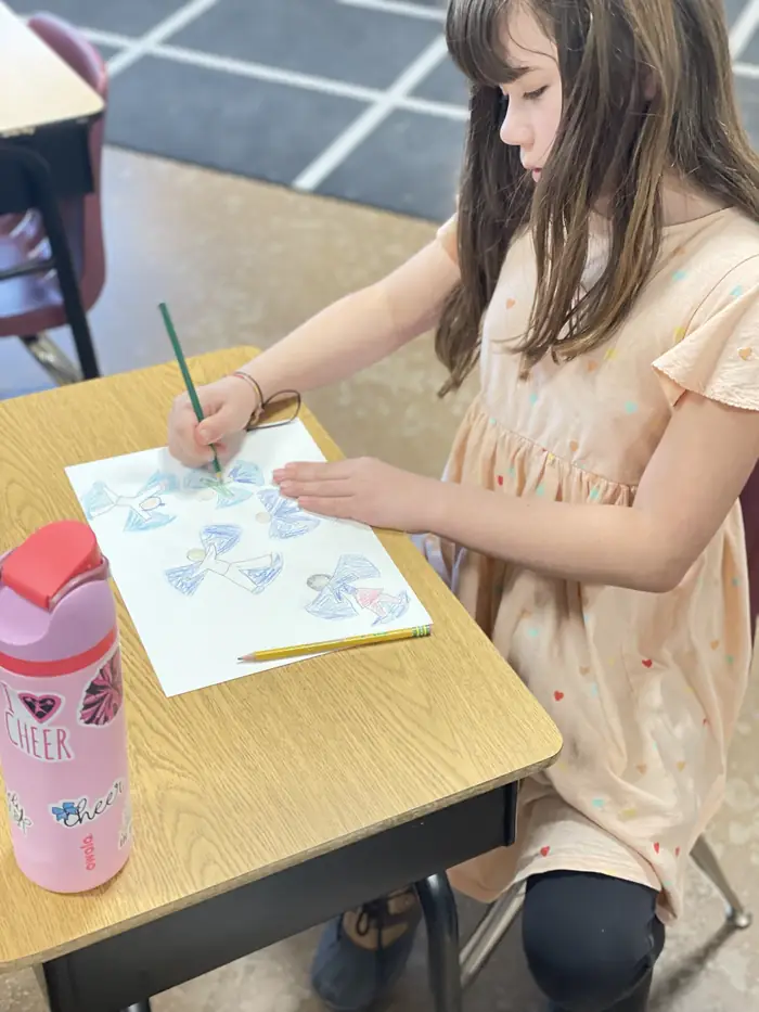 A Cornerstone student colouring a drawing at her desk in art class