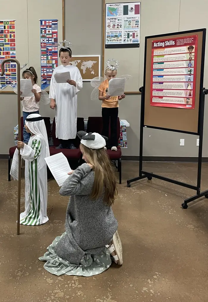 Cornerstone students in angel and shepherd costumes reading from scripts at a Readers Theater rehearsal