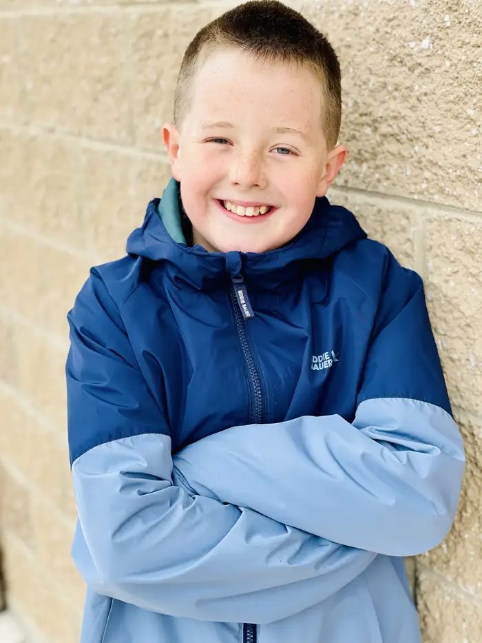 A Cornerstone student smiling with his arms folded outside the school